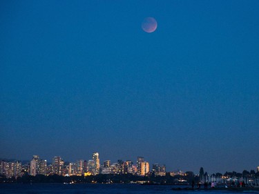 The moon rises over downtown buildings during a "supermoon" eclipse in Vancouver, B.C., on Sunday, September 27, 2015. A so-called supermoon is when the moon makes its closest approach to Earth, appearing larger and brighter than usual. It coincides with a full lunar eclipse where Earth, the moon and sun are lined up. The combination hasn't been seen since 1982 and won't happen again until 2033.