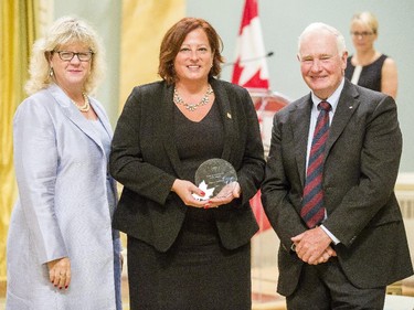 Nancy Gauthier of Public Works and Government Services Canada, center, receives the Public Service Award of Excellence on behalf of the Strategic Reengineering Team for Employee Innovation from Janice Charette, clerk of the privy council, left, and David Johnston, Governor General of Canada, right, at Rideau Hall Wednesday September 16, 2015. (Darren Brown/Ottawa Citizen) - Assignment 121627