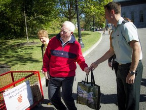 Gov. Gen. David Johnston, with his wife, Sharon, jokes with his aide-de-camp about the weight of the grocery bag full of food he is preparing to donate to the Ottawa Food Bank. Johnston was donating the food as part of the Savour Fall at Rideau Hall event on Saturday, Sept. 26, 2015.