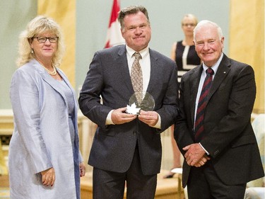 Sean Blane of Foreign Affair, Trade and Development Canada, center receives the Public Service Award of Excellence for Excellence in Citizen-Focused Service Delivery on behalf of the Vulnerable Persons Team from Janice Charette, clerk of the privy council, left, and David Johnston, Governor General of Canada, right, at Rideau Hall Wednesday September 16, 2015. (Darren Brown/Ottawa Citizen) - Assignment 121627