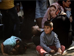 Syrian refugees and migrants wait with children at a registration camp in Presevo after their arrival in Serbia on August 30, 2015. The EU is grappling with an unprecedented influx of people fleeing war, repression and poverty in what the bloc has described as its worst refugee crisis in 50 years.