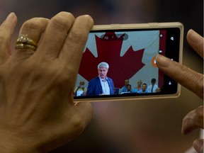 A woman takes a photo of Conservative Leader Stephen Harper as he delivers a speech to supporters during a campaign rally in Toronto on Monday.