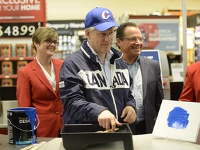 Prime Minister Stephen Harper tries out some blue paint during a campaign stop at a hardware store in St. Jacobs, Ontario. Monday, Sept. 21, 2105.
