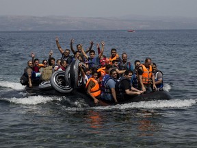 Syrian refugees arrive aboard a dinghy after crossing from Turkey, on the island of Lesbos, Greece on Monday.