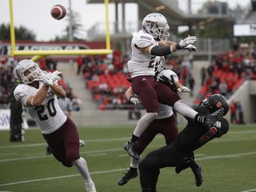 The ball is tipped by Randy Williams (middle in air) in a failed interception, landing into the hands of the Carleton Ravens' Nathaniel Behar (not pictured) for a game-winning touchdown with no time left.