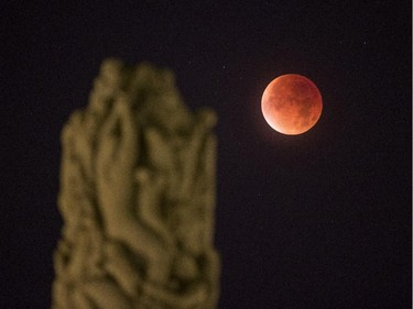 The perigee full moon, or supermoon appears red on the autumn sky, seen from Vigeland Park in Oslo, Monday, Sept. 28, 2015.  Stargazers were being treated to a rare astronomical phenomenon when a total lunar eclipse combined with a so-called supermoon.  Those in the United States, Europe, Africa and western Asia can view the coupling, weather permitting, Sunday night or early Monday.