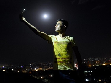 An Afghan man is illuminated by the light from his phone while taking a selfie on the top of the Wazir Akbar Khan hill in Kabul, as a view of the "supermoon" is seen in the background. For the first time in decades, skygazers are in for the double spectacle on September 28 of a swollen "supermoon" bathed in the blood-red light of a total eclipse. The celestial show, visible from the Americas, Europe, Africa, west Asia and the east Pacific, will be the result of the Sun, Earth and a larger-than-life, extra-bright Moon lining up for just over an hour from 0211 GMT.