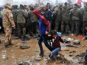 Migrants and refugees wait in the mud and under the rain to cross the Greek-Macedonian border near the village of Idomeni, in northern Greece on September 10, 2015. More than 10 thousands refugees and migrants arrived in Piraeus from the overcrowded Greek islands, especially the island of Lesbos , in the last 24 hours.
