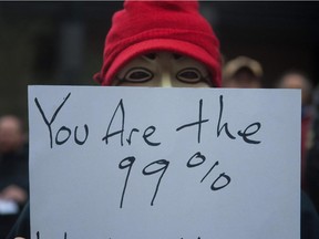 A masked protester holds a sign in Toroonto`s financial district at the Occupy Toronto movement on Saturday, Oct. 15, 2011.