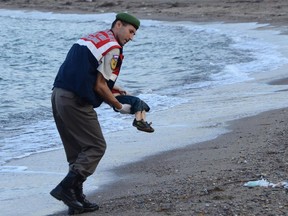 A Turkish police officer carries the lifeless body of Alan Kurdi off the shores in Bodrum, southern Turkey, on September 2, 2015 after a boat carrying refugees sank while reaching the Greek island of Kos. Thousands of refugees and migrants arrived in Athens on September 2, as Greek ministers held talks on the crisis, with Europe struggling to cope with the huge influx fleeing war and repression in the Middle East and Africa.