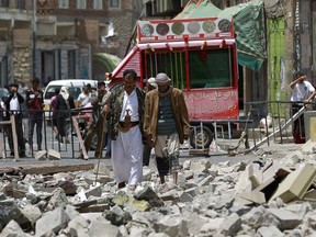 Yemenis make their way through debris following air strikes by the Saudi-led coalition on the rebel-controlled Chief of Staff's headquarters on September 16, 2015 in the capital Sanaa.