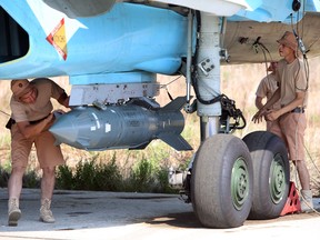 A picture taken on October 3, 2015 shows Russian air force technicians checking a Russian Su-34 fighter bomber at the Hmeimim airbase in the Syrian province of Latakia.