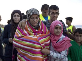 A Syrian family walks after they arrived with other refugees from Turkey to the shores of the Greek island of Lesbos, on a inflatable dinghy, Friday, Sept. 25, 2015.