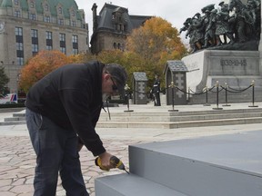 A worker installs risers ahead of ceremonies at the National War Memorial on Wednesday. A ceremony will be held Thursday to mark the first anniversary of the fatal shooting at the memorial of Cpl. Nathan Cirillo and the earlier killing of Warrant Officer Patrice Vincent in St-Jean-sur-Richelieu, Que.