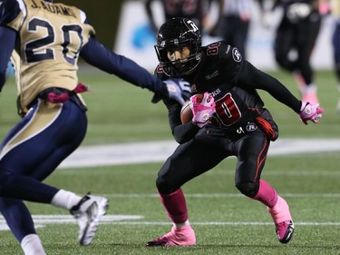 Chris Williams of the Ottawa Redblacks slips past Johnny Adams of the Winnipeg Blue Bombers during first half CFL action.
