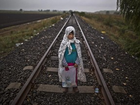 In this photo taken on Friday, Sept. 11, 2015, Syrian refugee Yasmeen Alhawal, 5, who came with her father Khalil from Aleppo, Syria, poses for a picture holding a bag of her belongings as they make their way through the railway at the Serbian-Hungarian border near Roszke, southern Hungary. "We just want to go to a country that treat us like humans. Our homes were destroyed, daily terrified not only from Bashar Assad but also from Islamic State, IS," said Yasmeen's father, Khalid Alhawal.