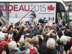 Liberal leader Justin Trudeau waves to a crowd of supporters as he boards his bus during a campaign stop Tuesday, October 13, 2015 in Stratford, Ont.