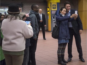People wait to take a photo with prime minister-designate Justin Trudeau as he greets constituents at a subway station in his Montreal riding Tuesday.