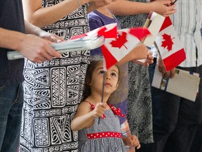 Lucy Galoyan, 3, waves the flag while her mom Araksya Mirzoyan received her citizenship as 50 new Canadians take the Citizenship Oath during a special Canada Day ceremony held at the Canadian Museum of History in Gatineau, Quebec. Photo taken at 10:11 on July 1, 2014.