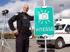 Const. Marc Leclerc stands next to a 'speed' sign that will warn drivers to slow down or risk getting a ticket from a photo radar van.