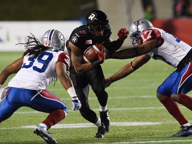 Ottawa Redblacks' Maurice Price, middle, runs the ball through Montreal Alouettes' Jerald Brown, left, and Billy Parker during the second half.