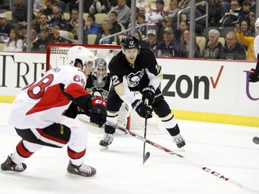 Ben Lovejoy #12 of the Pittsburgh Penguins clears a puck from Mike Hoffman #68 of the Ottawa Senators.