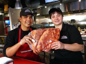 Ronel Bontigao, left, and Lea Wray hold a slab of bacon at the Bacon Factory.