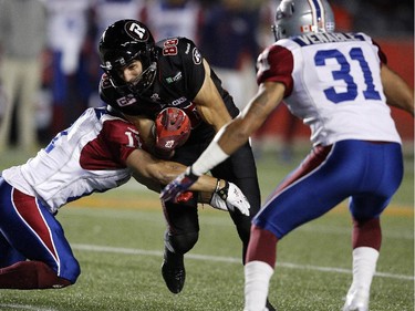 The Ottawa Redblacks' Brad Sinopoli, 88, is tackled by Montreal Alouettes' Chip Cox, 11, while Winston Venable, 31, looks on during the first half.