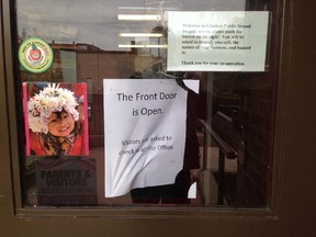 Note on the normally locked front door of Glashan Public School on Arlington Avenue advises visitors to check in at the school office.