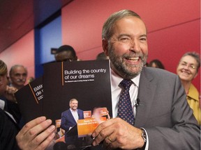 NDP leader Tom Mulcair holds up his party's platform book at a town hall meeting Friday, October 9, 2015 in Montreal.