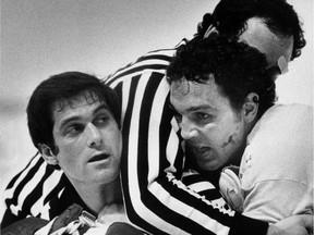 Officials restrain Saskatchewan-born Dave (Tiger) Williams during one of several brawls in an NHL playoff game in 1978. Williams was one of the most penalized players in league history.