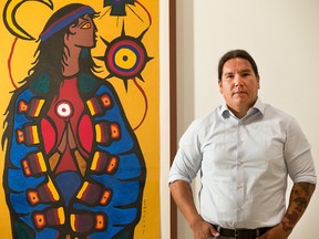 Waub Rice, novelist and CBC TV reporter, photographed with a Norval Morrisseau painting in the Ajagemo gallery on Elgin Street on Aug. 24, 2015. (Wayne Cuddington/ Ottawa Citizen)
