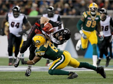 Hugh Charles #28 of the Ottawa Redblacks is hit by Cauchy Muamba #8 of the Edmonton Eskimos during first half Grey Cup 103 action at Investors Group Field on November 29, 2015 in Winnipeg, Manitoba, Canada.