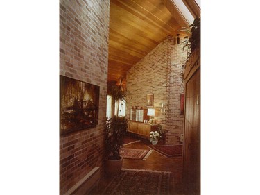 The foyer on the right opens to the dining and living rooms (background) and the hallway (foreground), which leads to the bedrooms. A painting on the left by local artist Bill Zuro depicts the house.