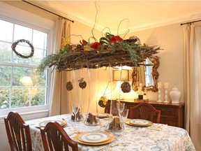Tall glass vases form pillars for a dining room centrepiece of twigs, yellow and red roses, winter greens and more.
