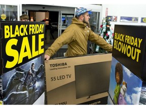 A customer carries a large TV to the checkout at an Ottawa Best Buy store on Black Friday, shortly after the store's 6 a.m. opening.