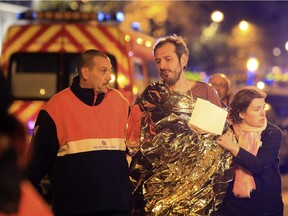 A man is being evacuated from the Bataclan theater after a shooting in Paris, Friday Nov. 13, 2015.  French President Francois Hollande declared a state of emergency and announced that he was closing the country's borders.
