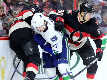 Alex Chaisson, right, and Milan Michalek, left, tussle with Vancouver's Ben Hutton for the puck behind Vancouver's net.