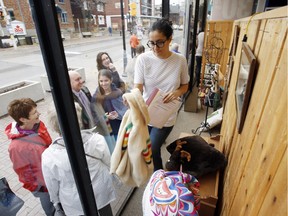 Alli Asudeh grabs a jacket for a shopper from the front window display of St. Vincent de Paul thrift shop on Wellington Street as people who had lined up as early as 4:30 a.m. to grab some of the Hudsons Bay themed items look on Friday Nov. 06, 2015.