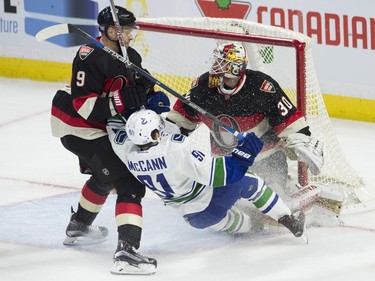 Ottawa Senators left wing Milan Michalek battles with Vancouver Canucks center Jared McCann in front of goalie Andrew Hammond during first period NHL action.
