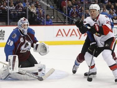 Ottawa Senators right wing Chris Neil, right, swings at the puck after it bounced off Colorado Avalanche goalie Reto Berra, of the Czech Republic, during the second period of an NHL hockey game Wednesday, Nov. 25, 2015, in Denver.