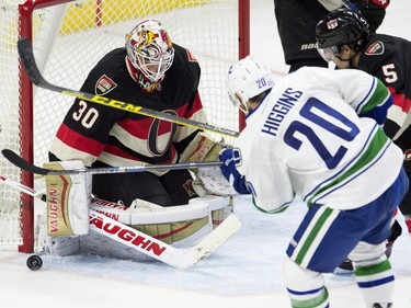 Vancouver Canucks left wing Chris Higgins shoots on Ottawa Senators goalie Andrew Hammond under pressure from Senators defenseman Cody Ceci (5) during second period NHL action.