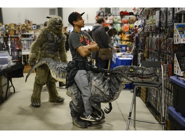 Cosplayer rests the dinosaur head on a chair as he browses for merchandise at Pop Expo.