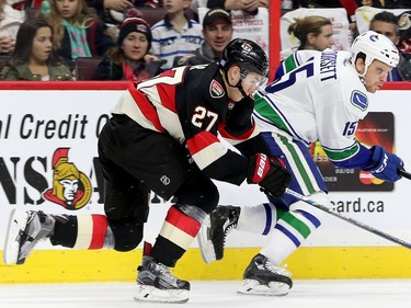 Curtis Lazar chases after the puck behind Vancouver's Derek Dorsett.