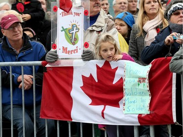 Danielle Johnson, 9, with her flag and thank-you sign  looks for the troops as the National Remembrance Day Ceremony takes place at the National War Memorial in Ottawa.