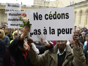 Two men holding a placard reading "don't give into fear" attend a gathering at the city Hall of Bordeaux, southwestern France, on November 20, 2015 as part of a public tribute to the victims of the November 13 Paris attacks.