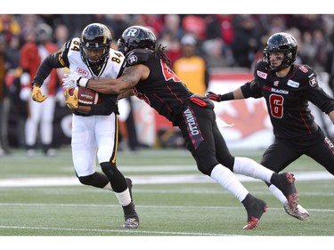 Hamilton Tiger-Cats's Bakari Grant (84) is tackled by Ottawa Redblacks's Damaso Munoz (45) as Antoine Pruneau (6) looks on during first half action in the CFL East Division final in Ottawa, Sunday November 22, 2015.
