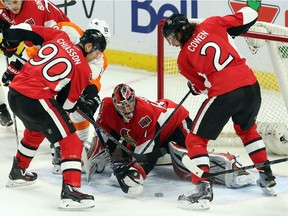 Ottawa Senators goalie Craig Anderson (41) tries to reach the puck as teammates Alex Chiasson (90) and Jared Cowan (2) attempt to clear during first period NHL hockey action, in Ottawa, on Saturday, Nov. 21, 2015.
