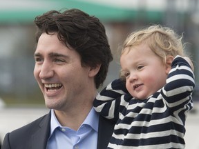 Canadian Prime Minister Justin Trudeau laughs as he walks to the government plane holding his son Hadrien as they leave the United Kingdom Thursday November 26, 2015 in Luton, England. Trudeau is heading to Malta for the Commonwealths Heads of Government meeting.