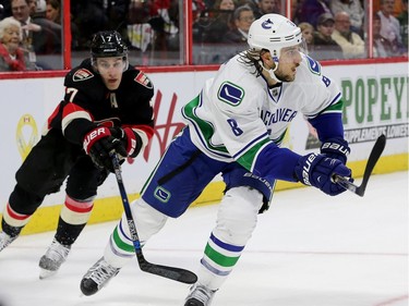 Kyle Turris chases Christopher Tanev around the net for the puck.